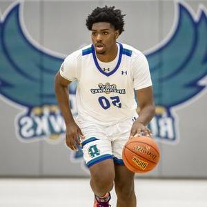 Male basketball player with Riverhawk logo behind him